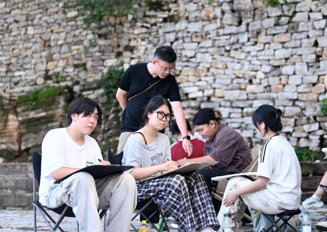(260805) -- TIANJIN, Aug. 5, 2026 (Xinhua) -- Visitors sketch in Xijingyu Village, Jizhou District of north China's Tianjin Municipality, Aug. 4, 2026. During summer vacation, Xijingyu Village has attracted lots of visitors. Known as the "Stone Village", it is famous for its distinctive houses and alleys built of stones. (Xinhua/Zhao Zishuo)
