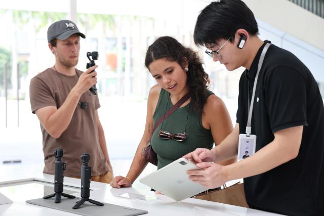 (260805) -- SHENZHEN, Aug. 5, 2026 (Xinhua) -- This photo taken on June 24, 2026 shows foreign tourists buying handheld camera equipment at a flagship shop of DJI in Shenzhen, south China's Guangdong Province. With the deep application of the achievements of emerging industries, many inbound foreign tourists choose science and technology tour as the theme of their journey in the Chinese cities. 
  In Shenzhen, foreign tourists are attracted by AI applications and technology scenarios in daily life, such as AI glasses, smart robots and unmanned delivery service. (Xinhua/Liang Xu)