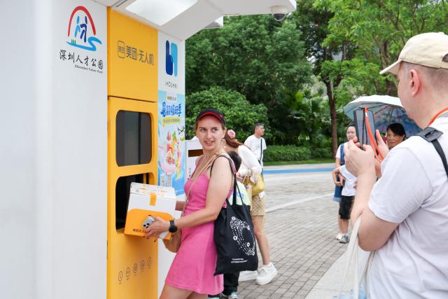 (260805) -- SHENZHEN, Aug. 5, 2026 (Xinhua) -- Foreign tourists experience Meituan's unmanned delivery service at a park in Shenzhen, south China's Guangdong Province, Aug. 3, 2026. With the deep application of the achievements of emerging industries, many inbound foreign tourists choose science and technology tour as the theme of their journey in the Chinese cities. 
  In Shenzhen, foreign tourists are attracted by AI applications and technology scenarios in daily life, such as AI glasses, smart robots and unmanned delivery service. (Xinhua/Liang Xu)