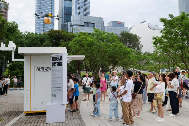 (260805) -- SHENZHEN, Aug. 5, 2026 (Xinhua) -- Tourists watch Meituan's unmanned delivery at a park in Shenzhen, south China's Guangdong Province, Aug. 3, 2026. With the deep application of the achievements of emerging industries, many inbound foreign tourists choose science and technology tour as the theme of their journey in the Chinese cities. 
  In Shenzhen, foreign tourists are attracted by AI applications and technology scenarios in daily life, such as AI glasses, smart robots and unmanned delivery service. (Xinhua/Liang Xu)