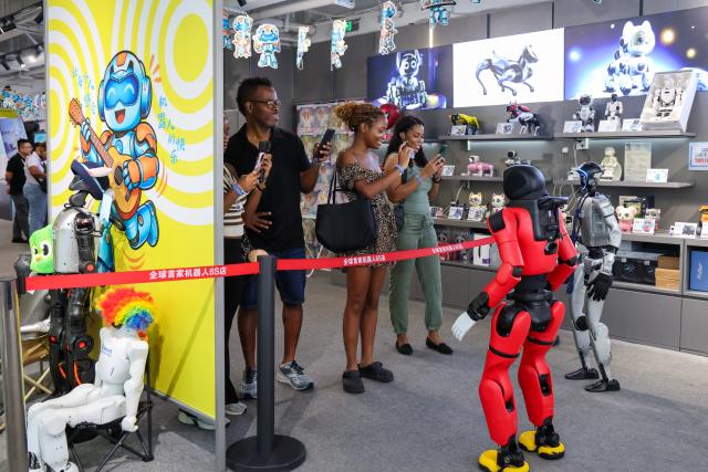 (260805) -- SHENZHEN, Aug. 5, 2026 (Xinhua) -- Tourists from Jamaica interact with a humanoid robot at a robot shop in Longgang District of Shenzhen, south China's Guangdong Province, Aug. 4, 2026. With the deep application of the achievements of emerging industries, many inbound foreign tourists choose science and technology tour as the theme of their journey in the Chinese cities. 
  In Shenzhen, foreign tourists are attracted by AI applications and technology scenarios in daily life, such as AI glasses, smart robots and unmanned delivery service. (Xinhua/Liang Xu)
