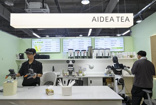 (260805) -- SHANGHAI, Aug. 5, 2026 (Xinhua) -- Staff members train a robot to work in a retail scenario at Maniformer, a physical AI data service platform, in Shanghai, east China, Aug. 5, 2026. In Shanghai's tech companies like AGIBOT and Maniformer, embodied intelligence robots are trained in household, retail, sorting, production and other real-world scenarios, to advance their AI capabilities for real-life use. (Xinhua/Chen Haoming)