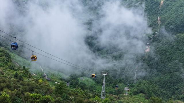 (260805) -- SHAOYANG, Aug. 5, 2026 (Xinhua) -- An aerial drone photo taken on Aug. 5, 2026
shows tourists taking cable cars to enjoy the valley scenery at the Dahuayao scenic area in Longhui County, Shaoyang City, central China's Hunan Province. During midsummer, Huxingshan Yao Township embraces a tourism boom thanks to its alpine climate, rich intangible cultural heritage and folk traditions. (Photo by Zeng Yong/Xinhua)