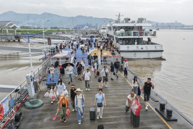 (260805) -- HANGZHOU, Aug. 5, 2026 (Xinhua) -- A drone photo shows passengers returning to a port in Pingyang County, east China's Zhejiang Province, Aug. 5, 2026.
  As Typhoon Dolphin, the 13th typhoon of 2026, is approaching the East China Sea, Zhejiang activated an emergency response along its coastal areas from 6 p.m. Wednesday. (Photo by Su Qiaojiang/Xinhua)