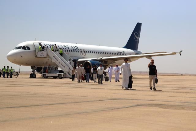 (260805) -- DEIR AL-ZOUR, Aug. 5, 2026 (Xinhua) -- Passengers disembark from the first flight of Syrian Airlines from Kuwait at Deir al-Zour International Airport in Deir al-Zour province, eastern Syria, Aug. 5, 2026. The first direct commercial flight from Kuwait landed Wednesday at Deir al-Zour International Airport in eastern Syria, marking the return of international commercial air services to the airport after more than a decade. (Str/Xinhua)
