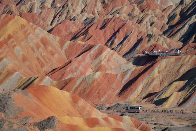 (260806) -- BEIJING, Aug. 6, 2026 (Xinhua) -- Tourists visit the Zhangye Danxia Scenic Area, renowned for its Danxia landforms featuring striking red sandstone formations, in Zhangye, northwest China's Gansu Province, Aug. 4, 2026. The scenic area in Gansu has entered its peak tourism season since August, with the average daily number of visitors surpassing 25,000. (Xinhua/Liu Keying)