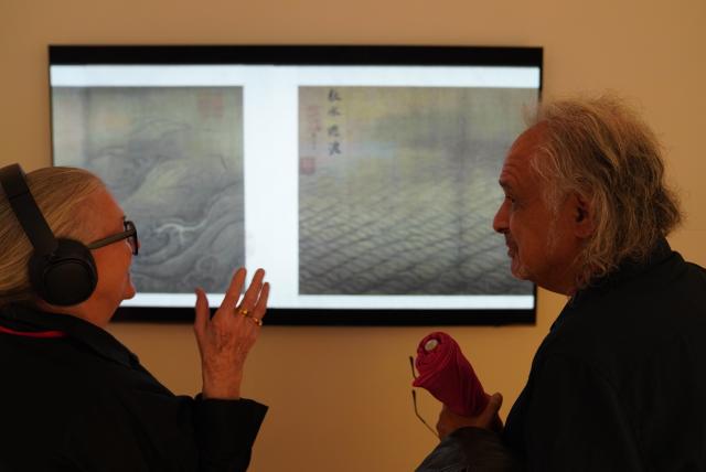 (260806) -- NEW YORK, Aug. 6, 2026 (Xinhua) -- A visitor listens to Chinese music in front of a screen showing ancient paintings during "The Unheard Melody: Exhibition of Music in Chinese Paintings" in New York, the United States, Aug. 5, 2026. The exhibition opened here on Wednesday. Featuring musical imagery from the art of ancient Chinese painting, it showcases a curated selection of masterpieces inspired by music from the Song Dynasty (960-1127), and invites visitors to explore the sounds and stories embedded within the artworks. (Xinhua/Zhang Fengguo)