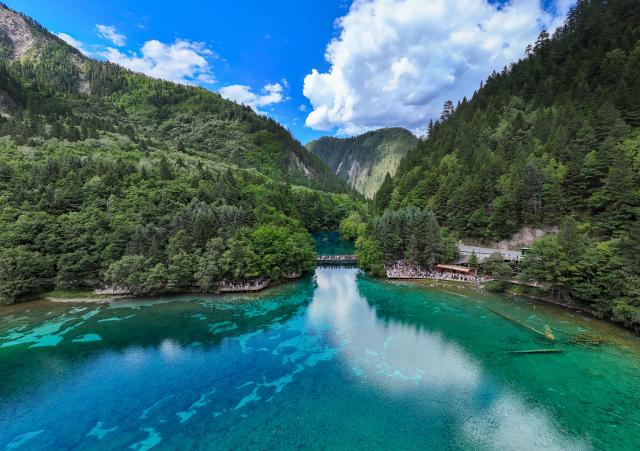 (260806) -- JIUZHAIGOU, Aug. 6, 2026 (Xinhua) -- A drone photo taken on Aug. 5, 2026 shows a view at the Jiuzhaigou scenic spot in southwest China's Sichuan Province. Jiuzhaigou is known for its spectacular waterfalls, lush forests, serene plateau lakes and karst rock formations, making it a popular destination for international tourists. (Xinhua/Wang Xi)