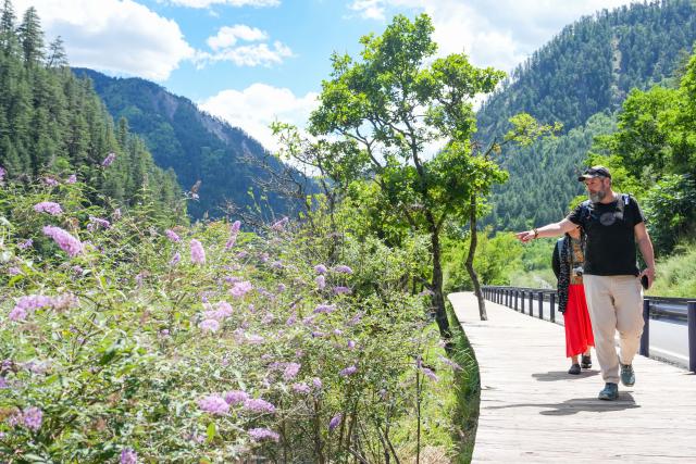 (260806) -- JIUZHAIGOU, Aug. 6, 2026 (Xinhua) -- Tourists from France have fun at the Jiuzhaigou scenic spot in southwest China's Sichuan Province, Aug. 5, 2026. Jiuzhaigou is known for its spectacular waterfalls, lush forests, serene plateau lakes and karst rock formations, making it a popular destination for international tourists. (Xinhua/Wang Xi)