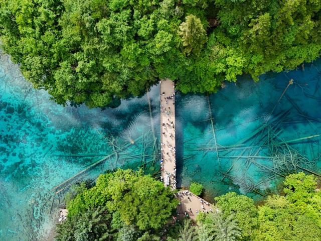 (260806) -- JIUZHAIGOU, Aug. 6, 2026 (Xinhua) -- An aerial drone photo taken on Aug. 5, 2026 shows tourists enjoying themselves at the Jiuzhaigou scenic spot in southwest China's Sichuan Province. Jiuzhaigou is known for its spectacular waterfalls, lush forests, serene plateau lakes and karst rock formations, making it a popular destination for international tourists. (Xinhua/Wang Xi)