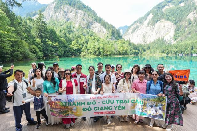 (260806) -- JIUZHAIGOU, Aug. 6, 2026 (Xinhua) -- Tourists from Vietnam pose for a group photo at the Jiuzhaigou scenic spot in southwest China's Sichuan Province, Aug. 6, 2026. Jiuzhaigou is known for its spectacular waterfalls, lush forests, serene plateau lakes and karst rock formations, making it a popular destination for international tourists. (Xinhua/Wang Xi)
