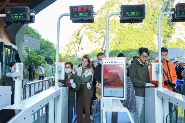 (260806) -- JIUZHAIGOU, Aug. 6, 2026 (Xinhua) -- Tourists queue up to check in at the Jiuzhaigou scenic spot in southwest China's Sichuan Province, Aug. 6, 2026. Jiuzhaigou is known for its spectacular waterfalls, lush forests, serene plateau lakes and karst rock formations, making it a popular destination for international tourists. (Xinhua/Wang Xi)