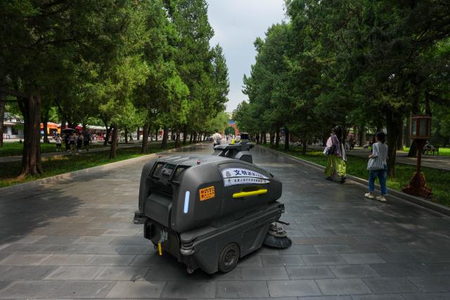 (260806) -- BEIJING, Aug. 6, 2026 (Xinhua) -- A robot cleans a pavement at the Temple of Heaven Park in Beijing, capital of China, Aug. 6, 2026.
  Fourteen municipal parks in Beijing have recently introduced a variety of new robots. These robots are now performing tasks such as cleaning, smart inspection, guided tours, water rescue, landscape maintenance, and ecological monitoring, bringing smart services into daily public life. (Xinhua/Ju Huanzong)