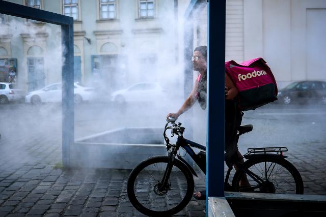 (260806) -- BUDAPEST, Aug. 6, 2026 (Xinhua) -- A delivery man cools off under a misting system in Budapest, Hungary, Aug. 6, 2026. Hungarian authorities on Tuesday extended the country's highest-level heat alert until midnight on Friday as forecasts indicate the ongoing heatwave will continue across the country. (Photo by David Balogh/Xinhua)