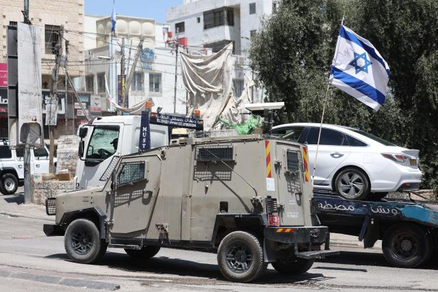 (260806) -- JERUSALEM, Aug. 6, 2026 (Xinhua) -- An Israeli military vehicle sets up a roadblock by the roadside near the Qalandiya checkpoint, north of Jerusalem, Aug. 6, 2026. Israeli military and police forces have intensified security operations in and around Jerusalem, as persistent violence across the West Bank drives up regional tensions recently. (Photo by Jamal Awad/Xinhua)