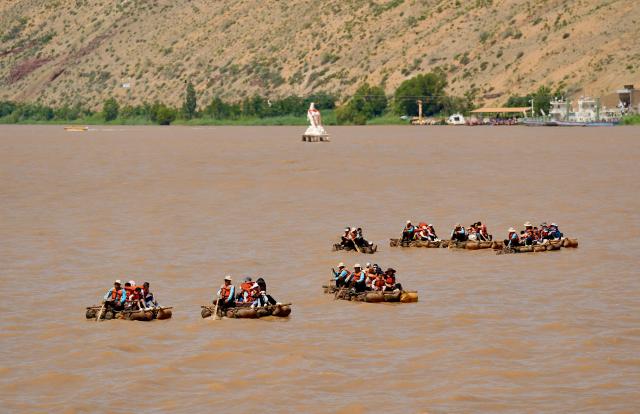 (260807) -- ZHONGWEI, Aug. 7, 2026 (Xinhua) -- Tourists take sheepskin rafts on the Yellow River at the Shapotou scenic area in Zhongwei, northwest China's Ningxia Hui Autonomous Region, Aug. 6, 2026. The Shapotou scenic area features a unique landscape where desert, the Yellow River, mountain and oasis converge. During the peak summer tourism season, the scenic area has witnessed a surge in visitors, with daily arrivals exceeding 20,000 at its peak. (Xinhua/Yang Zhisen)