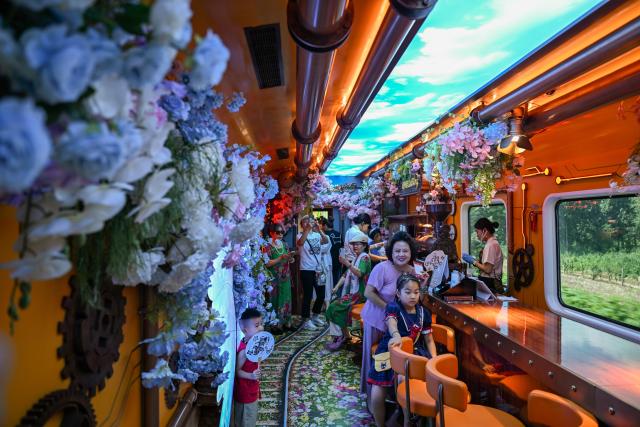 (260807) -- BEIJING, Aug. 7, 2026 (Xinhua) -- Passengers pose for photos inside a steampunk garden-themed carriage of the Tianjin Fantasy Express, July 29, 2026. (Xinhua/Sun Fanyue)