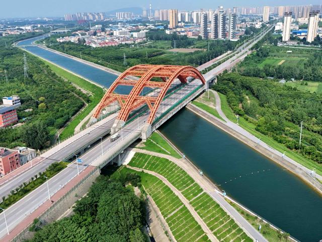 (260807) -- NANYANG, Aug. 7, 2026 (Xinhua) -- An aerial drone photo taken on Aug. 7, 2026 shows a bridge over the trunk canal of the middle route of the South-to-North Water Diversion Project in Nanyang, central China's Henan Province. The middle route of China's South-to-North Water Diversion Project has delivered more than 80 billion cubic meters of water as of Friday, benefiting nearly 118 million residents in 27 cities, the project operator announced.
   The mega water transfer project, the largest of its kind globally, channels water over long distances from the country's water-rich south to its northern regions, where hundreds of millions once endured "absolute water scarcity" as defined by United Nations standards. (Photo by Gao Song/Xinhua)