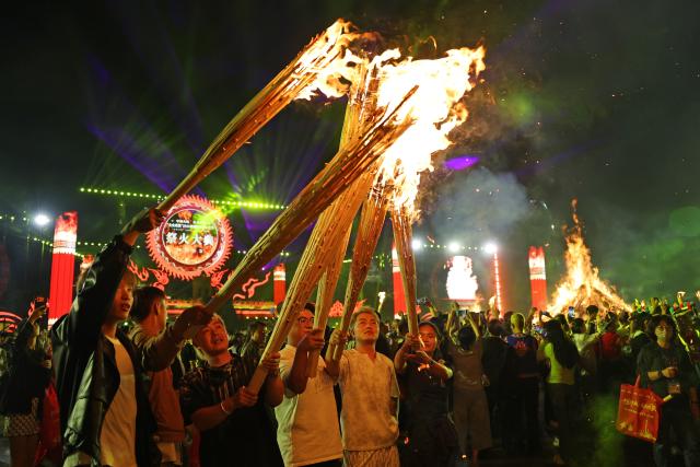 (260807) -- BEIJING, Aug. 7, 2026 (Xinhua) -- Tourists attend a torch festival revelry in Chuxiong Yi Autonomous Prefecture, southwest China's Yunnan Province, Aug. 6, 2026. The annual torch festivals were held in multiple locations on Thursday night, attracting crowds of tourists and locals from different ethnic groups. (Photo by Xia Tianyu/Xinhua)