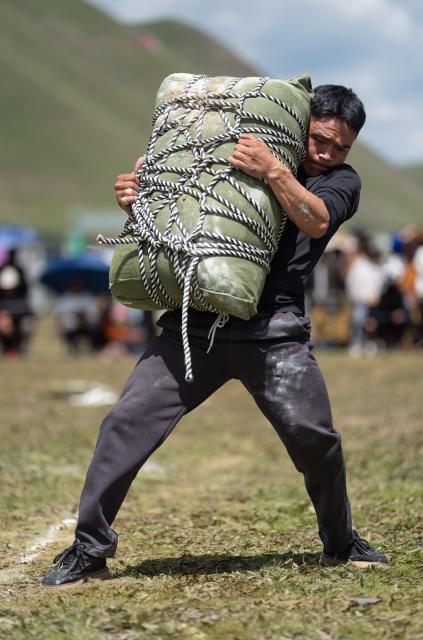 (260807) -- GARZE, Aug. 7, 2026 (Xinhua) -- A contestant takes part in a weight-carrying competition during the tent festival in Shiqu County of Garze Tibetan Autonomous Prefecture, southwest China's Sichuan Province, Aug. 7, 2026. A tent festival kicked off here on Friday. During the festival, local residents and tourists gather together, setting up tents and enjoying activities including horse racing, singing and dancing performances, and traditional sports competitions. (Xinhua/Jiang Hongjing)
