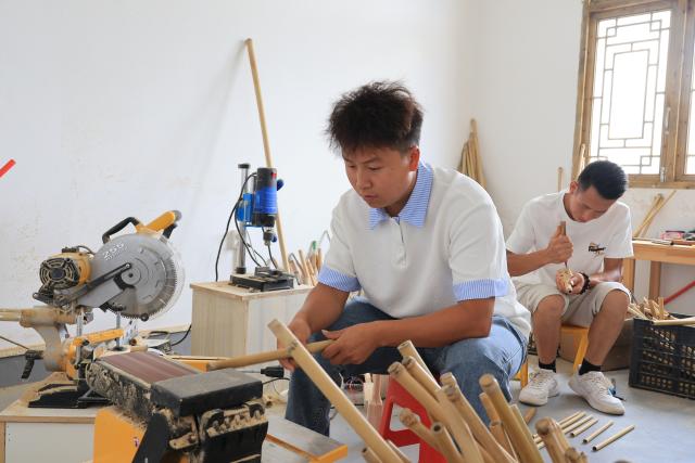 (260807) -- GUIYANG, Aug. 7, 2026 (Xinhua) -- Wang Pinggui (L) and Wang Tingliang craft Lusheng at a workshop in Gaopo Township of Guiyang, southwest China's Guizhou Province, July 11, 2026. TO GO WITH "Across China: Centuries-old ethnic musical instrument finds new guardians in rural southwest China" (Xinhua)