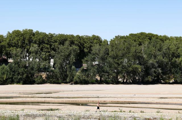(260807) -- ORLEANS, Aug. 7, 2026 (Xinhua) -- A man walks by the Loire River in Orleans, France, Aug. 7, 2026. The water level of the Loire River has dropped significantly due to persistent high temperatures and insufficient rainfall in France this summer. (Xinhua/Wu Huiwo)