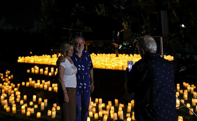 (260808) -- ROME, Aug. 8, 2026 (Xinhua) -- Spectators pose for photos ahead of the Candlelight Open Air concert at Villa Appia Antica in Rome, Italy, Aug. 7, 2026. Candlelight Open Air concert is a series of live musical performances held at iconic venues, including historic buildings, theaters, and monuments, illuminated by thousands of candles that create an intimate and special atmosphere. (Xinhua/Wang Kaiyan)