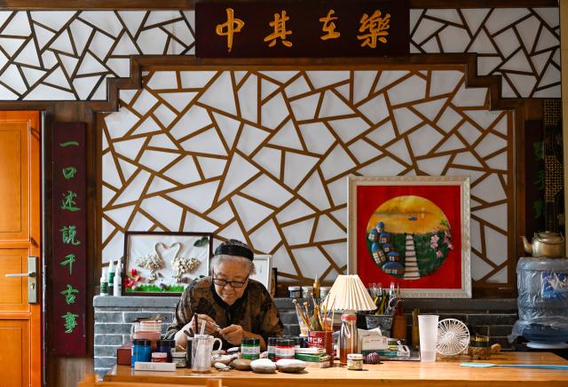 (260808) -- TIANJIN, Aug. 8, 2026 (Xinhua) -- Liu Anqin works on a stone painting at Xijingyu Village of Jizhou District in north China's Tianjin, Aug. 4, 2026. Liu Anqin, 82, never expected that retirement would open a new chapter in her life.
   Born in northeast China's Heilongjiang Province, Liu had no formal training in painting. After retirement, she enrolled in painting classes at an education program for the elderly and discovered her passion for art. Six years ago, Liu moved to Tianjin with her son. This spring, she rented a courtyard in Xijingyu Village and opened a homestay. Inspired by the village's rustic charm and stony landscape, Liu began painting on stones.
   Unlike painting on paper, stone painting is more challenging and requires greater patience. Yet Liu enjoys the process. Just months later, the courtyard is no longer just a homestay; it has become a small art gallery that attracts visitors to take photos and appreciate stone paintings.
   For Liu, meeting new friends and sharing her passion for art with young people is always a delight. "It's never too late to start something new, as long as you enjoy it," she said. (Xinhua/Zhao Zishuo)