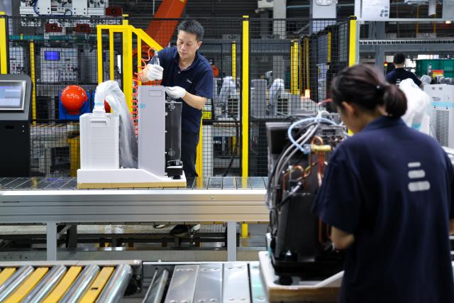 (260808) -- GUANGZHOU, Aug. 8, 2026 (Xinhua) -- Workers work on a production line for PortaSplit portable split air conditioners to be exported to the European market inside Midea's household air conditioner factory in Guangzhou, south China's Guangdong Province, Aug. 7, 2026. Demand for Chinese air conditioners has skyrocketed in many parts of Europe with heatwaves becoming more frequent, intense and prolonged this summer. PortaSplit, a portable split air conditioner from Chinese electronics manufacturer Midea, has become a hit product in the European market, with sales doubling compared to last year. Midea's household air conditioner factory in Guangzhou has ramped up production to meet international market demand. (Xinhua/Liang Xu)
