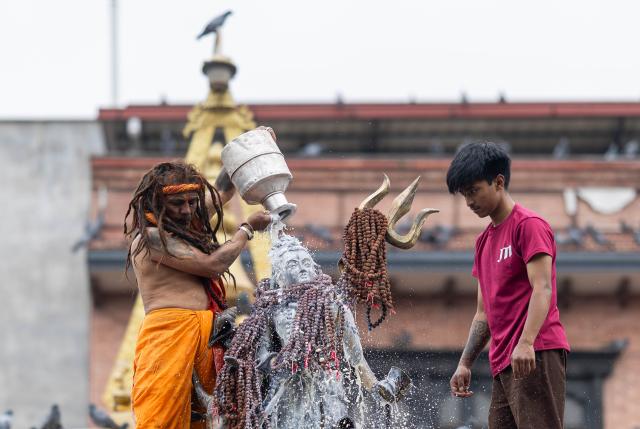 (260808) -- KATHMANDU, Aug. 8, 2026 (Xinhua) -- A priest (L) performs a ritual to mark the Hindu holy month of Shrawan in Kathmandu, Nepal, Aug. 8, 2026. (Photo by Sulav Shrestha/Xinhua)