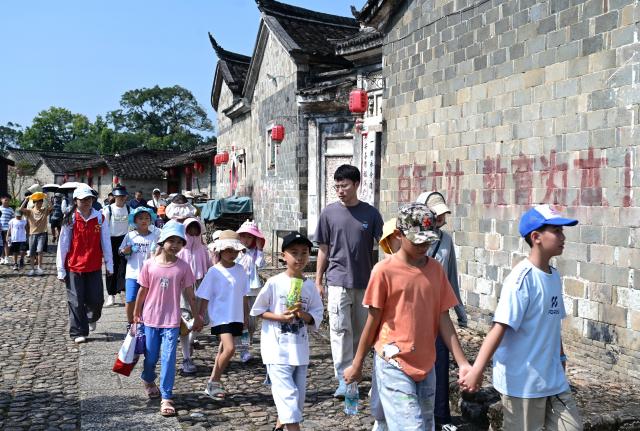 (260808) -- LONGYAN, Aug. 8, 2026 (Xinhua) -- Children led by their teachers visit Peitian Village in Xuanhe Town, Liancheng County, Longyan City, southeast China's Fujian Province, Aug. 6, 2026. Boasting a history of more than 800 years, Peitian Village is home to a complex of buildings from the Ming (1368-1644) and Qing (1644-1911) dynasties, as well as over 20 key cultural relic sites under state-level protection. It was listed as one of China's historic and cultural villages in 2005 and inscribed in the first batch of traditional Chinese villages catalog in 2012. Local authorities have injected new vitality into the village through efforts of integrated cultural and tourism development. (Xinhua/Lin Shanchuan)