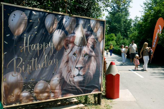 (260808) -- BUCHAREST, Aug. 8, 2026 (Xinhua) -- Visitors walk past a lion birthday celebration banner during an event marking the upcoming World Lion Day at Bucharest Zoo in Bucharest, Romania, Aug. 8, 2026. World Lion Day is observed on Aug. 10 every year to raise people's awareness of lion conservation. (Photo by Cristian Cristel/Xinhua)