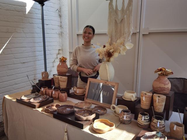 (260808) -- WINDHOEK, Aug. 8, 2026 (Xinhua) -- An exhibitor poses with her pottery works at Windhoek's first Potters' Market in Windhoek, Namibia, on August 8, 2026. TO GO WITH "Feature: Clay creations bring artists, public closer at Windhoek's inaugural Potters' Market" (Photo by Ndalimpinga Iita/Xinhua)