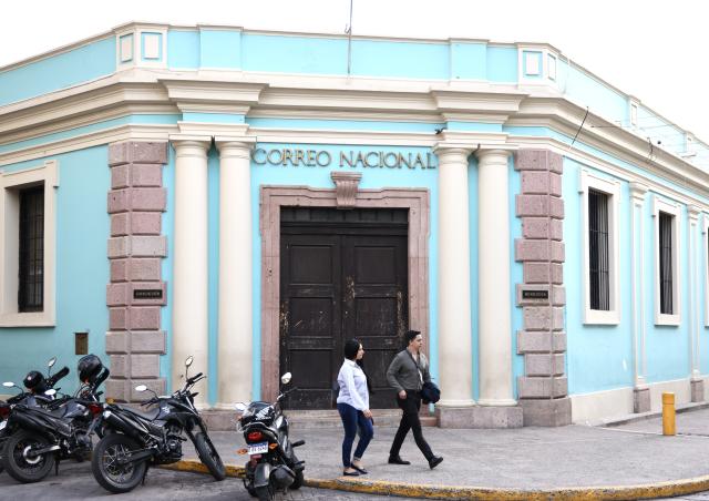 (260809) -- TEGUCIGALPA, Aug. 9, 2026 (Xinhua) -- Pedestrians walk past the national post office in the old town of Tegucigalpa, Honduras, on Aug. 6, 2026. Tegucigalpa, the capital of Honduras, is the country's political and economic center. Surrounded by mountains and hills, the city is known for its hilly terrain, colorful streets and vibrant urban life. (Xinhua/Liu Wenhui)