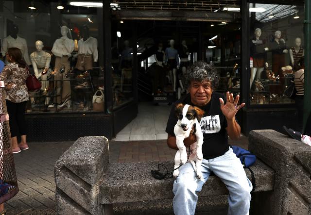 (260809) -- TEGUCIGALPA, Aug. 9, 2026 (Xinhua) -- A man relaxes with his pet dog in the old town of Tegucigalpa, Honduras, on Aug. 6, 2026. Tegucigalpa, the capital of Honduras, is the country's political and economic center. Surrounded by mountains and hills, the city is known for its hilly terrain, colorful streets and vibrant urban life. (Xinhua/Liu Wenhui)
