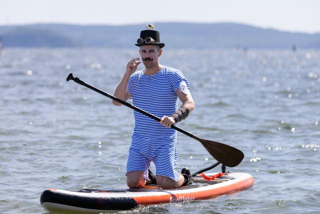 (260809) -- VLADIVOSTOK, Aug. 9, 2026 (Xinhua) -- A man participates in a paddleboard carnival in Vladivostok, Russia, Aug. 9, 2026. The Vladivostok paddleboard carnival was held here on Sunday, with participants dressed as jellyfish, pirates, mermaids, and other characters. (Photo by Andrey Matveenko/Xinhua)
