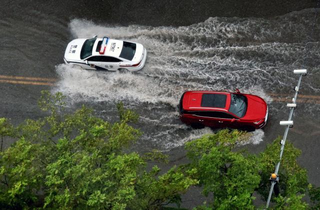 (260810) -- BEIJING, Aug. 10, 2026 (Xinhua) -- Vehicles drive through a waterlogged street in Jinshan District of east China's Shanghai, Aug. 10, 2026. Typhoon Dolphin is moving inland after making two landfalls along the coast of east China's Zhejiang Province and is expected to bring heavy precipitation to more than 10 provincial-level regions, according to China's National Meteorological Center on Monday.
   The center issued a blue typhoon warning on Monday morning, forecasting persistent heavy rainfall through Wednesday in regions including Zhejiang, Jiangsu, Henan and Hebei. Some areas are likely to experience torrential rain, thunderstorms and strong winds.
   Authorities in multiple localities have made all-out efforts in flood prevention and typhoon response. (Photo by Zhuang Yi/Xinhua)