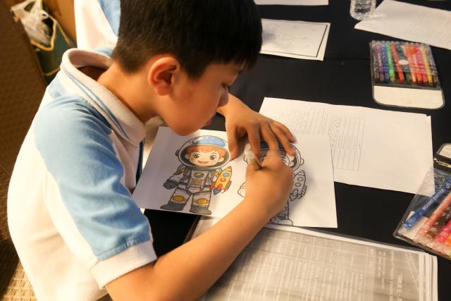 (260810) -- YANGON, Aug. 10, 2026 (Xinhua) -- A child takes part in a coloring activity during the opening ceremony of the "Weekly Cinema, Shared Stories" Film Exhibition at the National Theater in Yangon, Myanmar, Aug. 9, 2026. TO GO WITH "Asia-Pacific Community: Chinese space documentary inspires Myanmar students" (Xinhua/Myo Kyaw Soe)