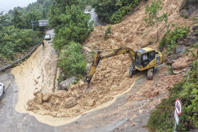 (260810) -- WENZHOU, Aug. 10, 2026 (Xinhua) -- A drone photo taken on Aug. 10, 2026 shows a staff member operating an excavator to clear the collapsed section of a road in Luojialiao Village in Wenzhou, east China's Zhejiang Province. Typhoon Dolphin is moving inland after making two landfalls along the coast of east China's Zhejiang Province and is expected to bring heavy precipitation to more than 10 provincial-level regions, according to China's National Meteorological Center on Monday. (Photo by Su Qiaojiang/Xinhua)