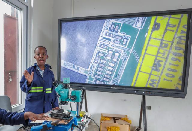 (260811) -- DAR ES SALAAM, Aug. 11, 2026 (Xinhua) -- A student explains circuit board features using a large electronic screen connected to a microscope during a practical skills class at De'kayra Pre and Primary School in Bagamoyo, Tanzania, Aug. 7, 2026. TO GO WITH "Feature: Learning by doing prepares Tanzanian children for future" (Xinhua/Emmanuel Herman)