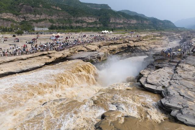 (260811) -- XI'AN, Aug. 11, 2026 (Xinhua) -- An aerial drone photo taken on Aug. 10, 2026 shows tourists visiting the Yellow River's Hukou Waterfall in northwest China's Shaanxi Province. (Xinhua/Shao Rui)