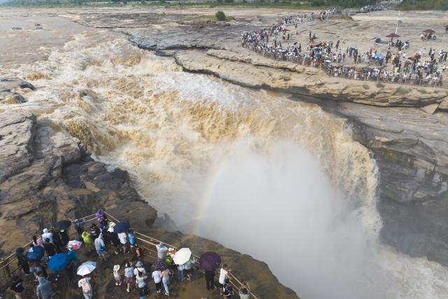 (260811) -- XI'AN, Aug. 11, 2026 (Xinhua) -- An aerial drone photo taken on Aug. 10, 2026 shows tourists visiting the Yellow River's Hukou Waterfall in northwest China's Shaanxi Province. (Xinhua/Shao Rui)