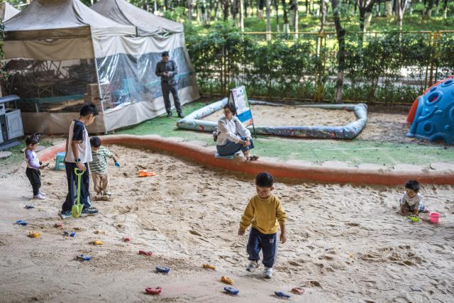 (260811) -- KUNMING, Aug. 11, 2026 (Xinhua) -- Children play at a playground beneath a flyover in Kunming, southwest China's Yunnan Province, Aug. 11, 2026. In recent years, Kunming has transformed some vacant areas beneath urban bridges and flyovers into public spaces for greenery, leisure, recreation and physical exercises, making the city more livable for residents. (Xinhua/Wang Guansen)