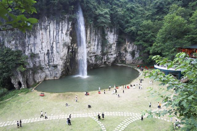 (260811) -- GUIYANG, Aug. 11, 2026 (Xinhua) -- Tourists enjoy themselves beside a waterfall in Anshun City, southwest China's Guizhou Province, Aug. 6, 2026. Best known for its karst landscape, Guizhou has made the best of karst caves to develop distinctive sites for cooling retreats. Featuring natural geological wonders, cooling enjoyment and water amusements, this emerging tourist experience has become a hit among locals and visitors alike. (Photo by Lu Wei/Xinhua)