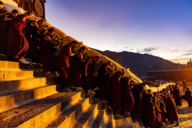 (260812) -- LHASA, Aug. 12, 2026 (Xinhua) -- Monks carry an enormous rolled-up thangka painting of Buddha at the Drepung Monastery in Lhasa, southwest China's Xizang Autonomous Region, Aug. 12. 2026.
  Celebrations marking the traditional Shoton Festival began in Lhasa on Wednesday. (Xinhua/Jiang Fan)