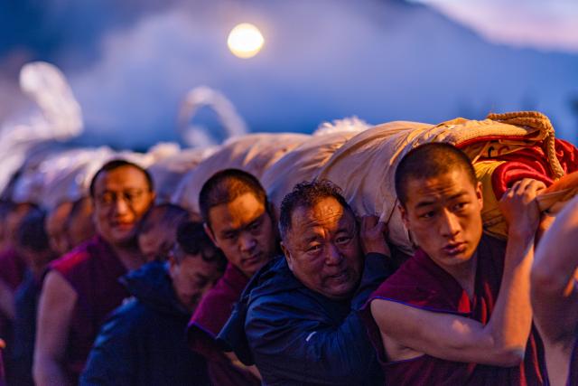 (260812) -- LHASA, Aug. 12, 2026 (Xinhua) -- People carry an enormous rolled-up thangka painting of Buddha at the Drepung Monastery in Lhasa, southwest China's Xizang Autonomous Region, Aug. 12. 2026.
  Celebrations marking the traditional Shoton Festival began in Lhasa on Wednesday. (Xinhua/Jiang Fan)