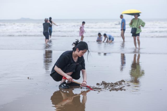 (260812) -- ZHOUSHAN, Aug. 12, 2026 (Xinhua) -- People have fun at the Nansha scenic area in Zhujiajian of Zhoushan City, east China's Zhejiang Province, Aug. 12, 2026.
  The Nansha scenic area reopened to the public on Wednesday following necessary safety checks and maintenance after Typhoon Dolphin weakened. (Xinhua/Xu Yu)