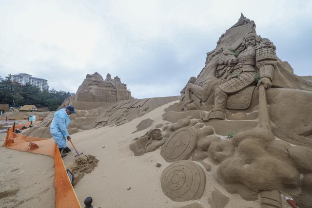 (260812) -- ZHOUSHAN, Aug. 12, 2026 (Xinhua) -- A staff member repairs a sand sculpture at the Nansha scenic area in Zhujiajian of Zhoushan City, east China's Zhejiang Province, Aug. 12, 2026.
  The Nansha scenic area reopened to the public on Wednesday following necessary safety checks and maintenance after Typhoon Dolphin weakened. (Xinhua/Xu Yu)