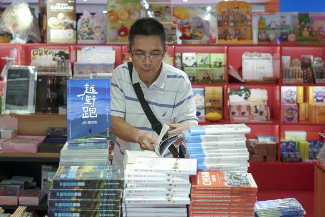 (260812) -- SHANGHAI, Aug. 12, 2026 (Xinhua) -- A man reads a book during the 2026 Shanghai Book Fair at the Shanghai Book City in Shanghai, east China, Aug. 12, 2026. Opening on Wednesday, the ongoing 2026 Shanghai Book Fair features two main venues, the Shanghai Exhibition Center and the Shanghai Book City. The cultural event will last until Aug. 18. (Photo by Su Chang/Xinhua)