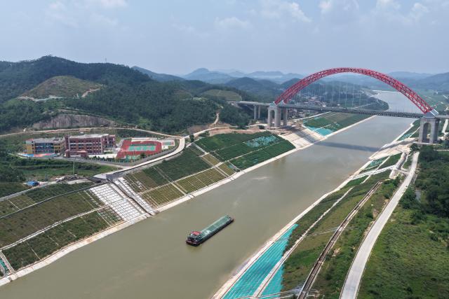 (260812) -- LINGSHAN, Aug. 12, 2026 (Xinhua) -- An aerial drone photo taken on Aug. 12, 2026 shows a trial vessel driving past the Jiuzhou Bridge over the Pinglu Canal in south China's Guangxi Zhuang Autonomous Region. Pinglu Canal started vessel trials on Wednesday, marking a key step toward the planned opening of this major Chinese waterway in September.
   The tests will assess navigation under both normal and adverse conditions and examine whether the canal's waterways, locks, anchorages, service areas and navigation facilities are ready for operation.
   Designed to accommodate vessels of up to 5,000 tonnes, the 134.2-km Pinglu Canal is China's first major river-to-sea canal project planned and coordinated at the national level since 1949.
   Stretching from the Pingtang River in Guangxi's Hengzhou City to the Beibu Gulf in the South China Sea, the canal is the backbone of the country's New International Land-Sea Trade Corridor, which has evolved into a strategic route linking China's inland regions with ASEAN and other global markets. (Xinhua/Zhou Hua)
